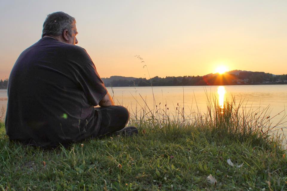 Torre, van achteren gezien, zittend in het gras bij een meer bij zonsondergang